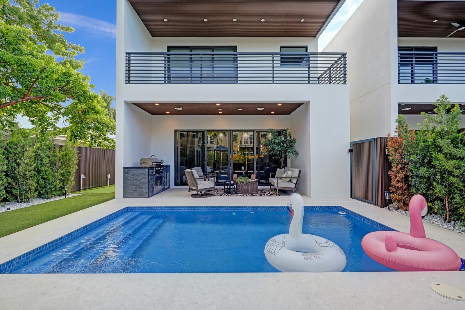Modern two-story rental exterior with pool, patio lounge, and outdoor grill