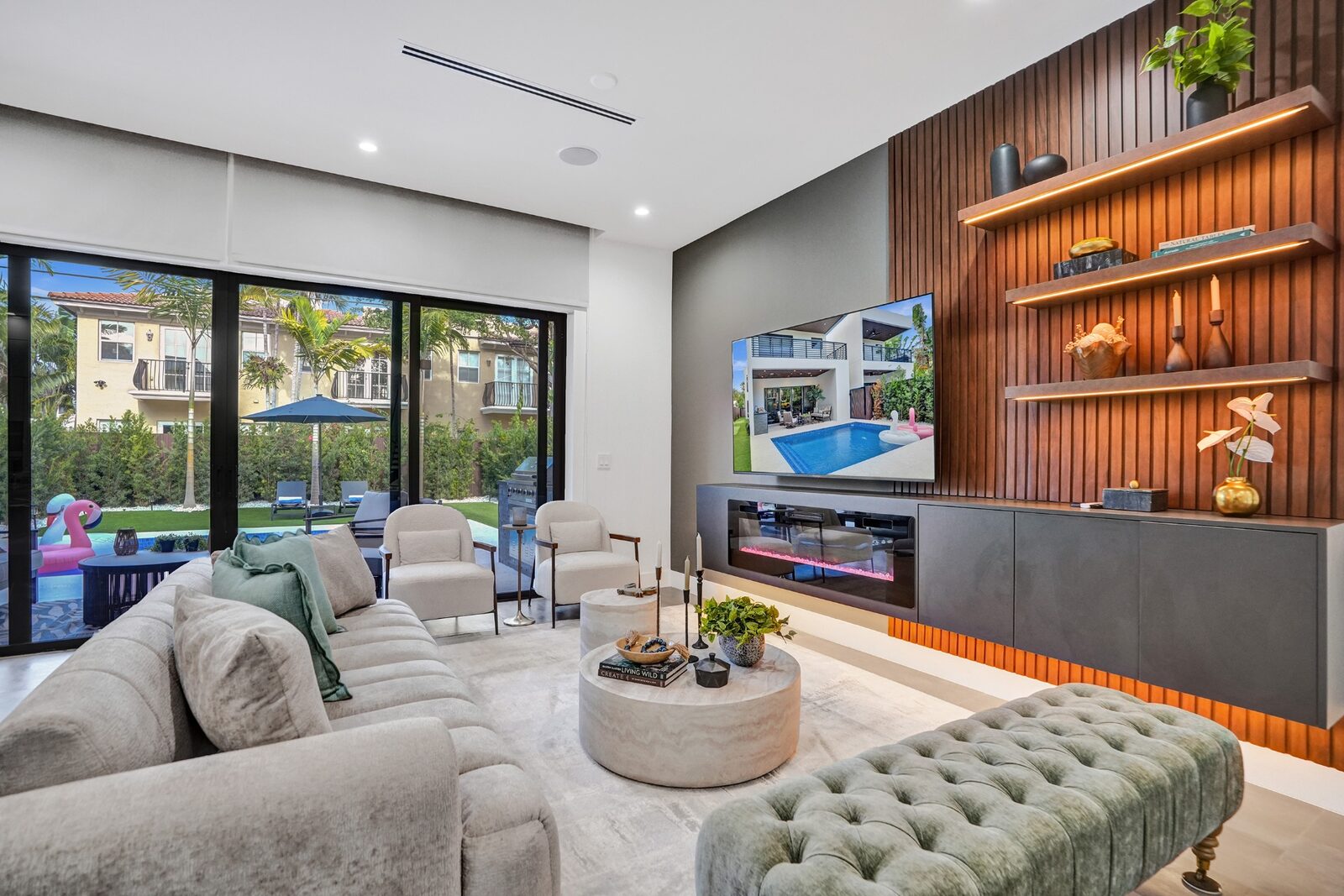 Luxury living room with fireplace, designer sectional, and pool view