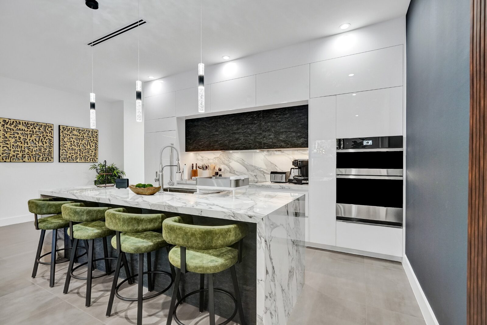 Modern chef's kitchen with marble waterfall island and green velvet bar stools