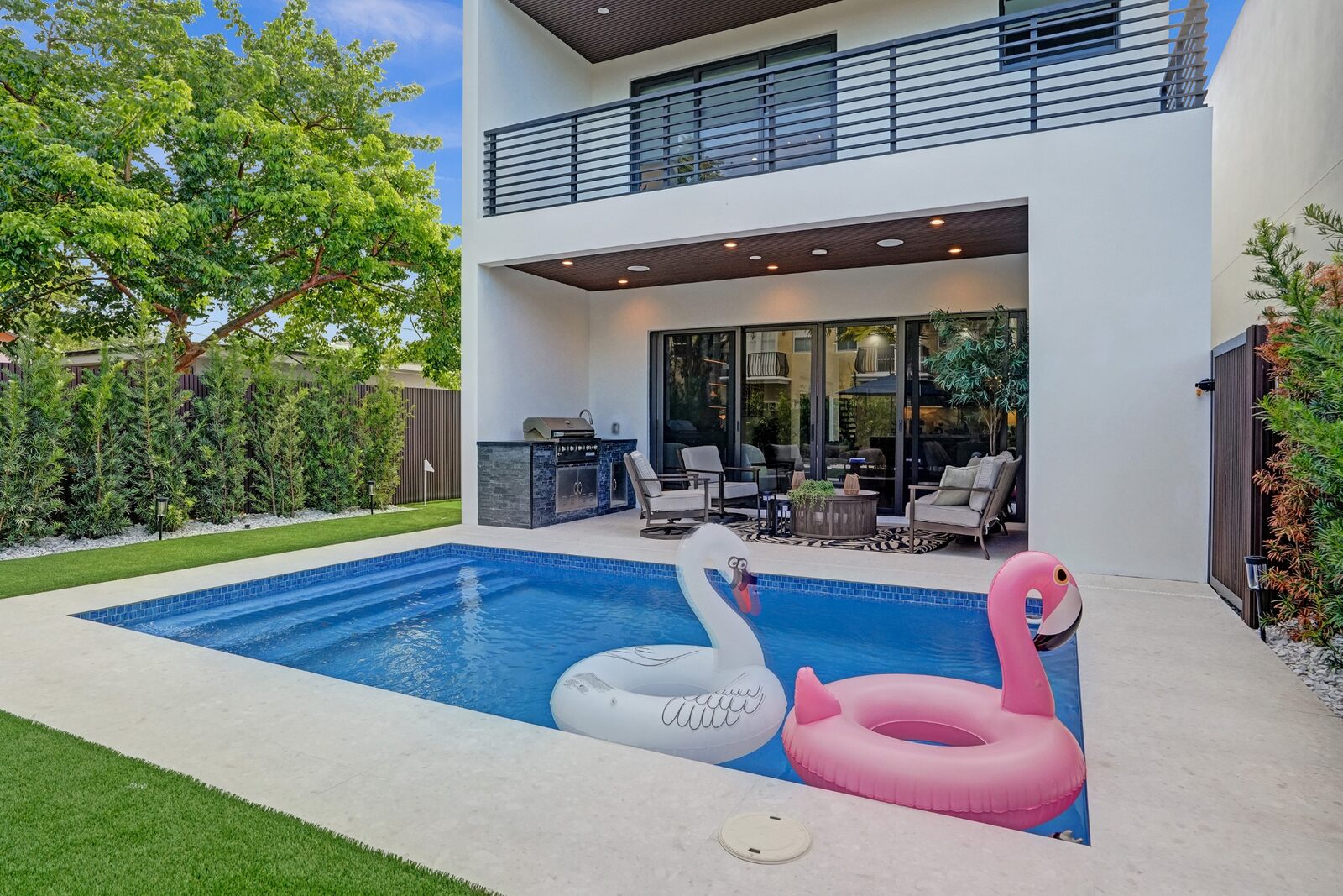 Private backyard pool and covered patio with outdoor kitchen at dusk